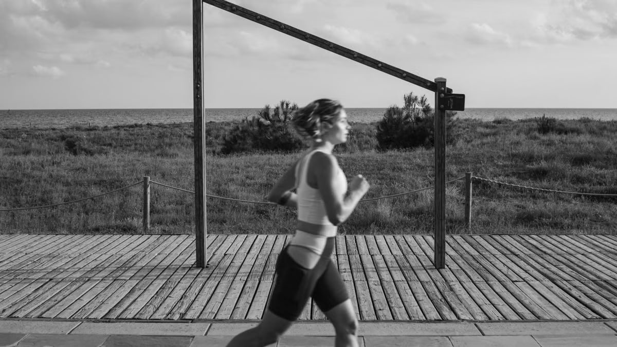 A woman jogs along a coastal boardwalk in Castelldefels, Spain, promoting fitness and outdoor exercise.